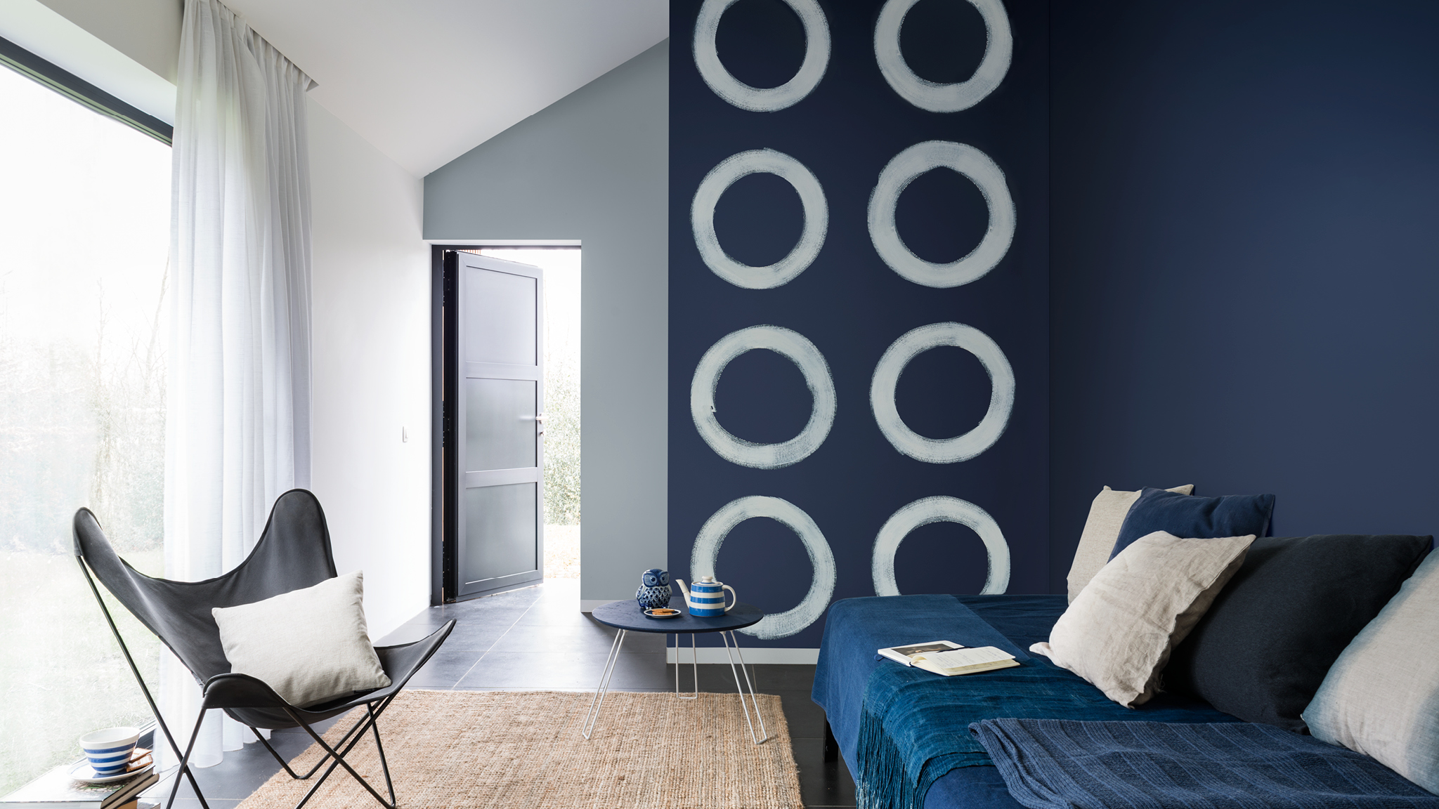 Pared con círculos azules El uso libre de formas pintadas a mano alzada puede darle un toque de creatividad dinámica a tu hogar.